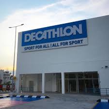 Exterior view of a Decathlon store with a large blue and white signboard displaying the slogan "Sport for All | All for Sport."