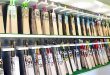 A display of premium cricket bats arranged neatly on shelves in a sports shop, showcasing various brands and models with vibrant designs.