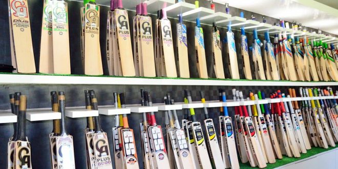 A display of premium cricket bats arranged neatly on shelves in a sports shop, showcasing various brands and models with vibrant designs.